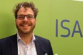 Raf Buyle looking at the camera in front of a green background.